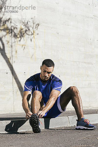 Afroamerikanischer Sportler in voller Länge beim Binden von Schnürsenkeln