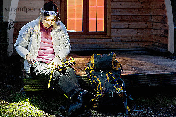 Frau beim Schärfen ihrer Steigeisen vor einer Campinghütte im Vereinigten Königreich
