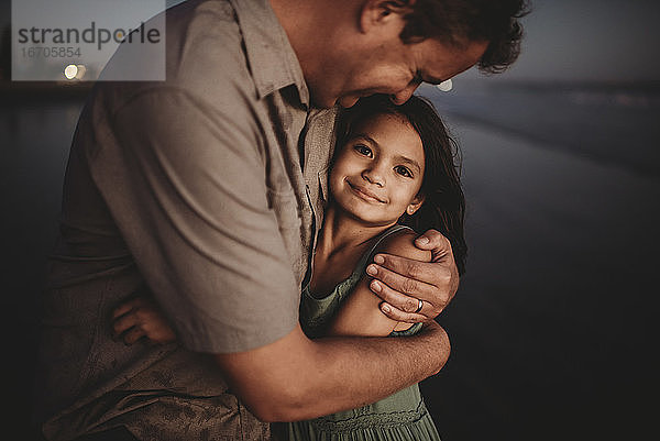 Liebender Vater umarmt schöne 8 Jahre alte Tochter mit dunklen Augen