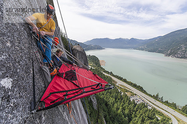 zwei Männer beim Aufbau einer Portaledge auf Squamish Chief mit Blick auf den Ozean