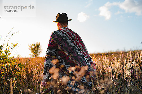 Mann im Poncho auf einem Feld  stimmungsvolle ländliche Szene