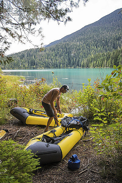 Mann am Seeufer  der seine Boote für eine Packrafting-Tour auf dem See vorbereitet.