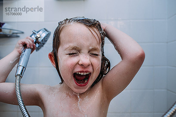 Nahaufnahme eines jungen Kindes  das beim Haarewaschen unter der Dusche singt