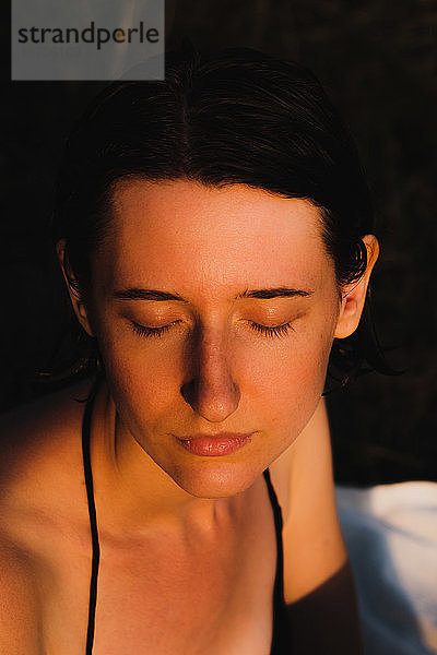Junge erwachsene Frau mit nassen Haaren bei Sonnenuntergang. Low-Key-Porträt einer