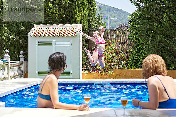 Frauen im Urlaub in einem Schwimmbad. Kinder spielen vor ihnen.
