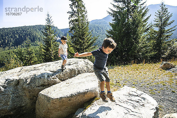 Junge Jungen springen und erkunden Felsen in der Natur.