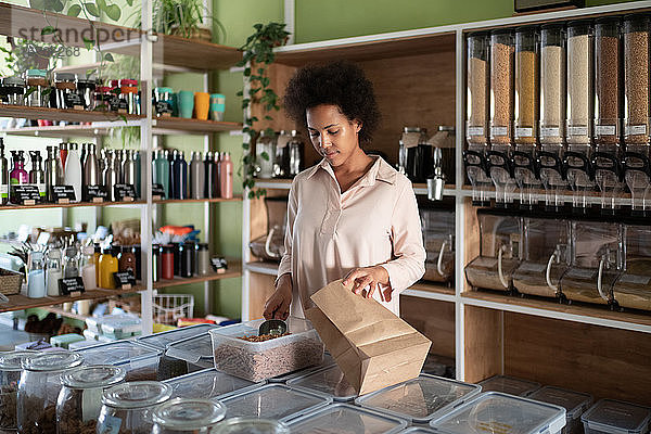 Afroamerikanische Verkäuferin packt Lebensmittel in Papiertüte