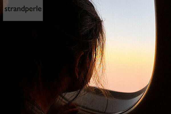 Kleines Mädchen schaut während des Flugs aus dem Flugzeugfenster