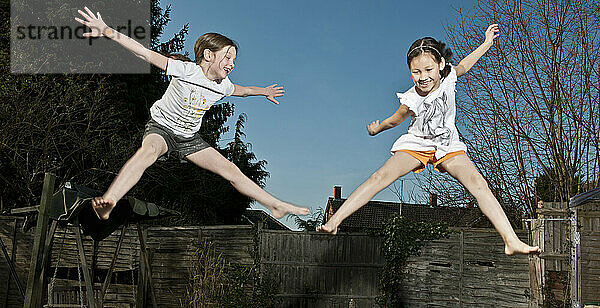 zwei junge Mädchen springen auf einem Trampolin in Woking - England