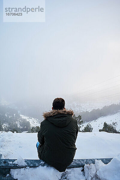 Junger Mann blickt an einem verschneiten Tag auf den Horizont