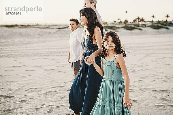 Glückliche Familie  die zusammen am Strand spazieren geht und sich an den Händen hält