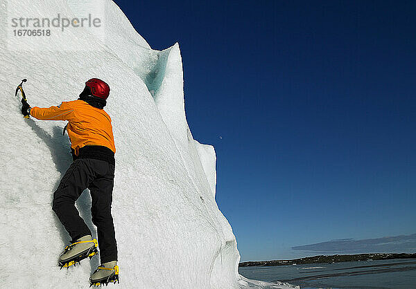 Mann klettert an der Seite eines Gletschers im Süden von Island