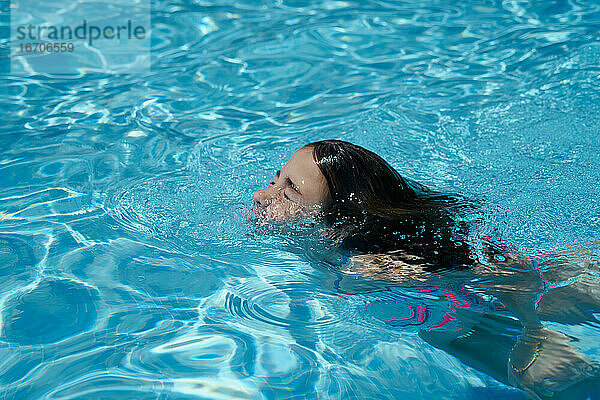 Glückliches lächelndes Mädchen  das schwimmt und Spaß im Schwimmbad hat