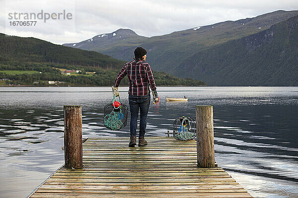 Ein Mann hält einen Krabbenkutter vor einem Dock in Norwegen