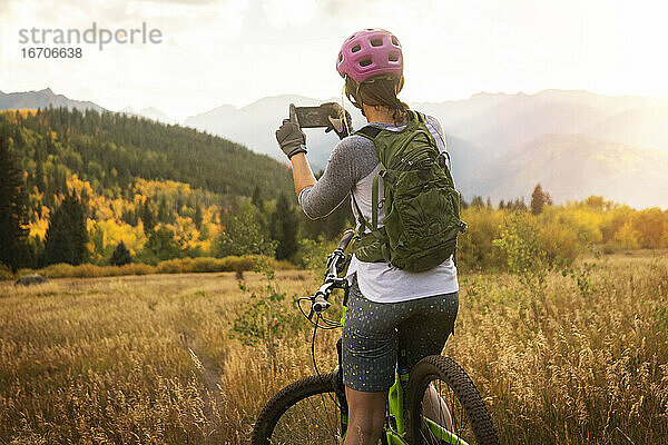 Rückansicht einer Frau  die beim Mountainbiken fotografiert
