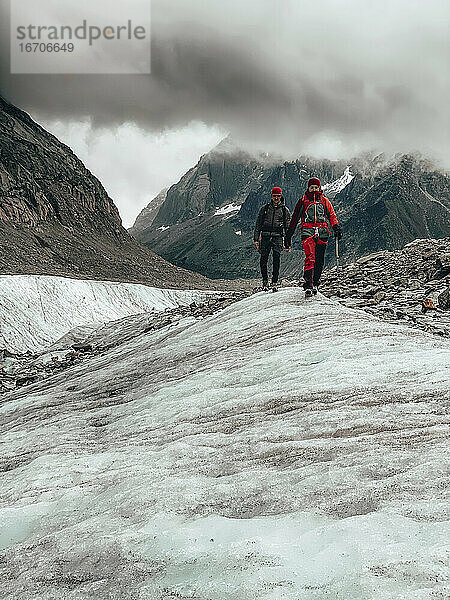 Zwei Bergsteiger beim Abstieg von einem Gletscher in Frankreich unter dramatischen Wolken