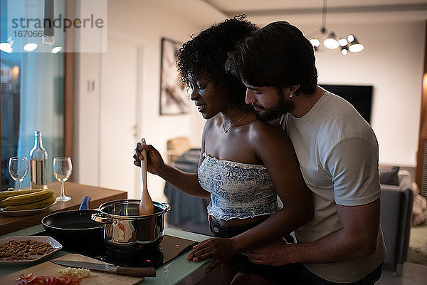 Mann hilft schwarzer Freundin bei der Zubereitung des Abendessens