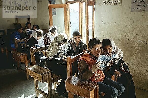 Neun Schüler in Klassenzimmer  ein Junge und ein Mädchen lesen in der ersten Bank  Potokh Primary School  Potokh  Wakhan-Korridor  Afghanistan  Asien