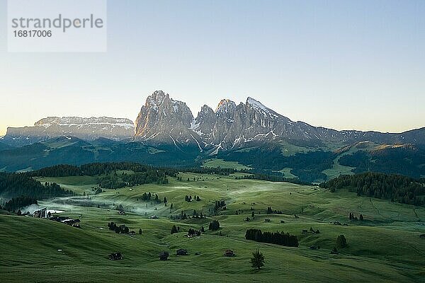 Drohnenaufnahme  Seiser Alm mit grünen Wiesen  Hütten und Nebel  hinten Langkofel und Plattkofel Seiser Alm  Südtirol  Italien  Europa