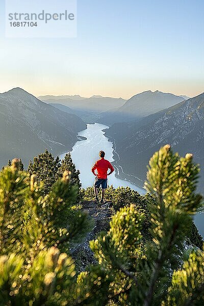 Bergsteiger  junger Mann blickt über Berglandschaft  Latschenkiefern am Gipfel des Bärenkopf  Ausblick auf den Achensee bei Sonnenuntergang  Karwendel  Tirol  Österreich  Europa