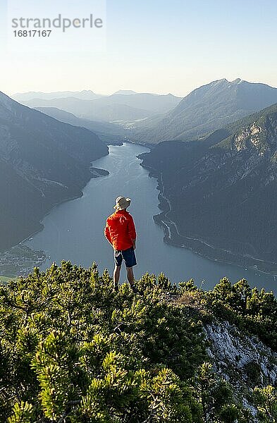 Bergsteiger  junger Mann blickt über Berglandschaft  Latschenkiefern am Gipfel des Bärenkopf  Ausblick auf den Achensee bei Sonnenuntergang  links Seekarspitze und Seebergspitze  Karwendel  Tirol  Österreich  Europa