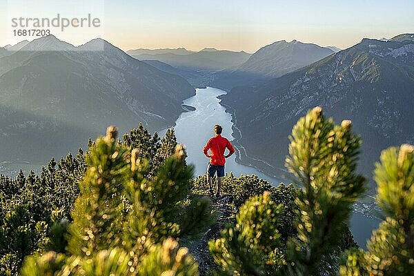 Bergsteiger  junger Mann blickt über Berglandschaft  Latschenkiefern am Gipfel des Bärenkopf  Ausblick auf den Achensee bei Sonnenuntergang  Karwendel  Tirol  Österreich  Europa