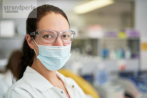 Porträt selbstbewusste Wissenschaftlerin mit Gesichtsmaske im Labor