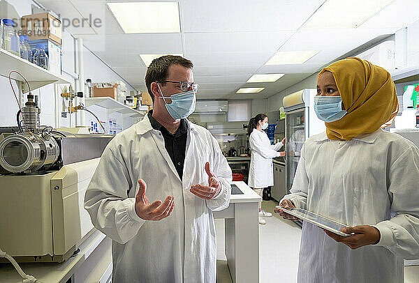 Wissenschaftler mit Gesichtsmasken sprechen im Labor
