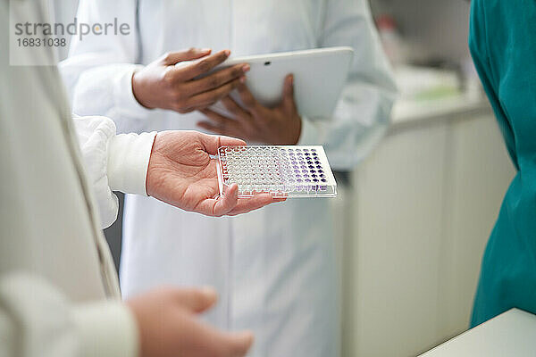 Wissenschaftler mit digitalem Tablet und Probentablett im Labor