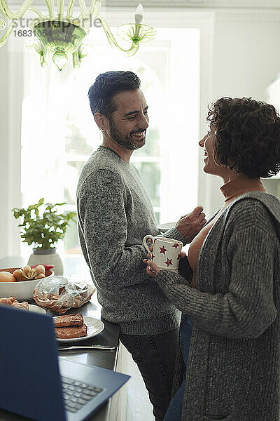 Glückliches Paar im Gespräch und Kaffee trinken in der Küche am Morgen