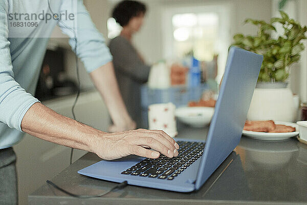 Close up Mann arbeitet von zu Hause am Laptop auf Küchentheke