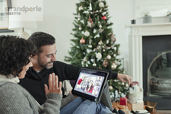 Glückliches Paar Video-Chat mit Familie auf digitalen Tablette an Weihnachten