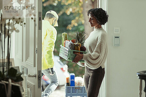 Frau erhält Lebensmittellieferung vom Kurier an der Haustür