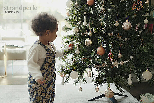 Nettes Baby Mädchen Blick auf Weihnachtsbaumschmuck