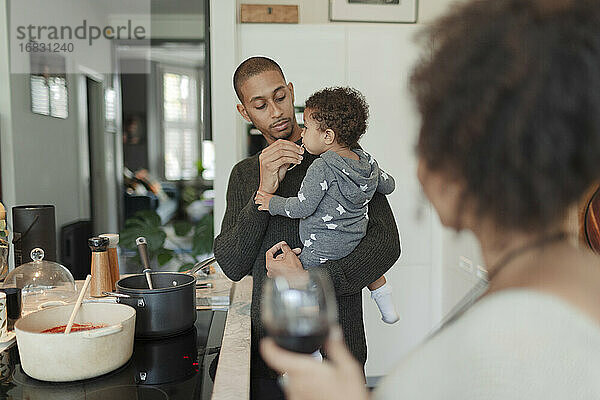 Vater hält Baby Tochter und Kochen Abendessen am Küchenherd