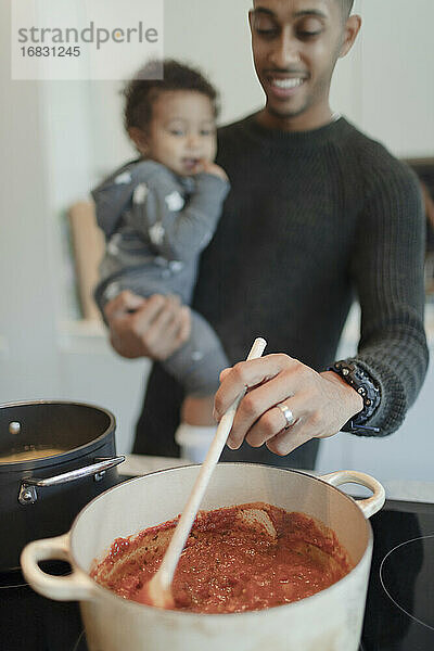 Vater hält Baby Tochter und Kochen Spaghetti am Herd