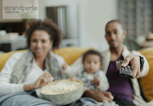 Familie mit Fernbedienung beim Fernsehen mit Popcorn auf dem Sofa