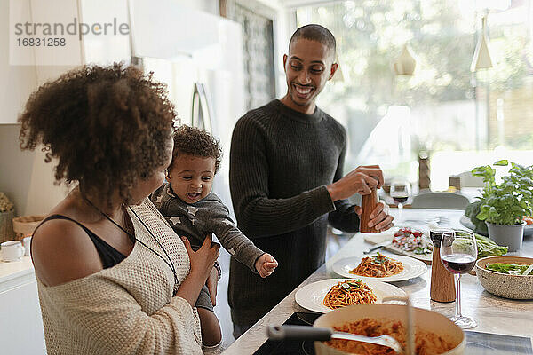 Glückliche Eltern mit Baby Tochter Kochen Spaghetti in der Küche