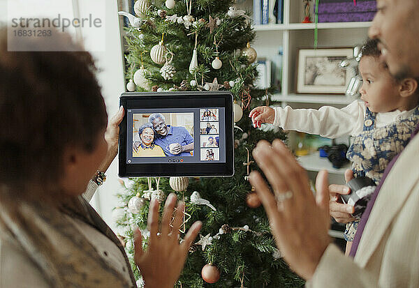 Familie im Videochat mit digitalem Tablet am Weihnachtsbaum