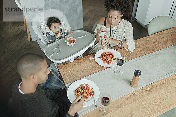 Familie essen Spaghetti am Esstisch und Hochstuhl