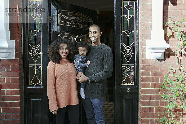 Porträt glückliche Eltern mit Baby Tochter an der Haustür von Haus