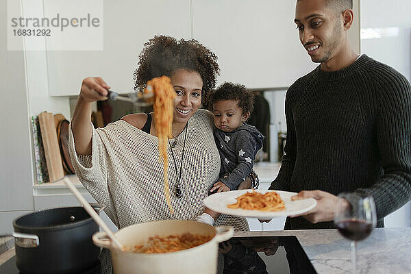 Eltern mit Baby Tochter kochen Spaghetti am Küchenherd