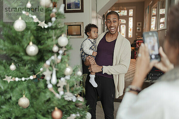 Glücklicher Vater und Baby Tochter posiert für Foto von Weihnachtsbaum