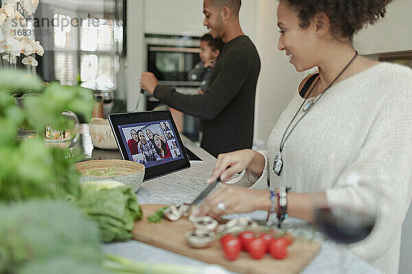 Familie beim Kochen und Videochatten am digitalen Tablet in der Küche