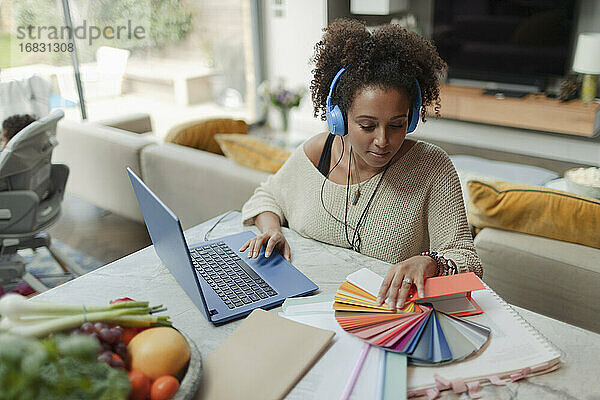 Weiblicher Designer mit Farbmustern  der von zu Hause aus am Laptop arbeitet