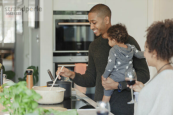 Glückliches Paar mit Baby Tochter Kochen Abendessen in der Küche