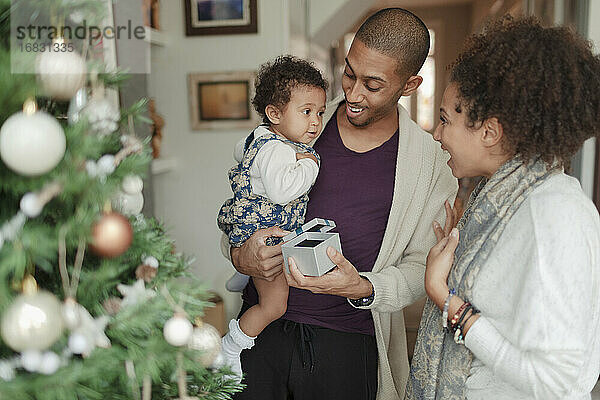 Glückliche Eltern und Baby Tochter Öffnung Weihnachtsgeschenke durch Baum