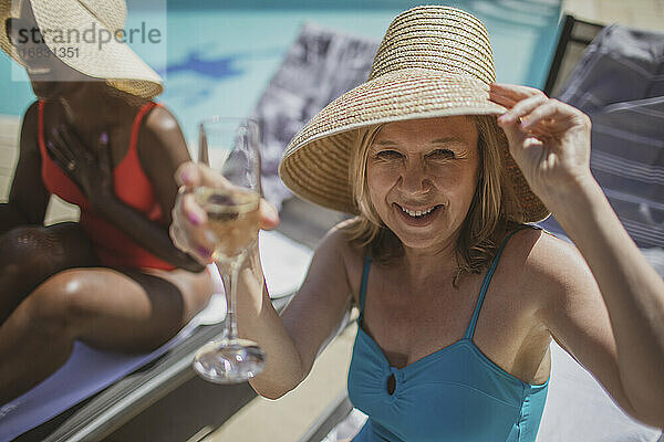 Porträt glücklich ältere Frau trinken Champagner am sonnigen Pool