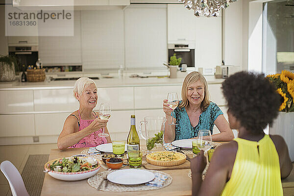 Senior Frauen Freunde genießen Weißwein mit Mittagessen am Esstisch