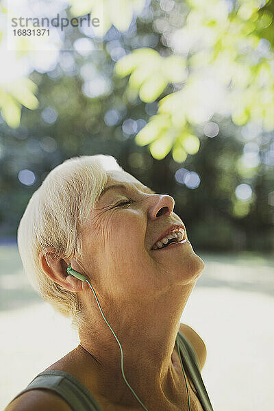 Glückliche sorglose ältere Frau  die mit Kopfhörern Musik hört